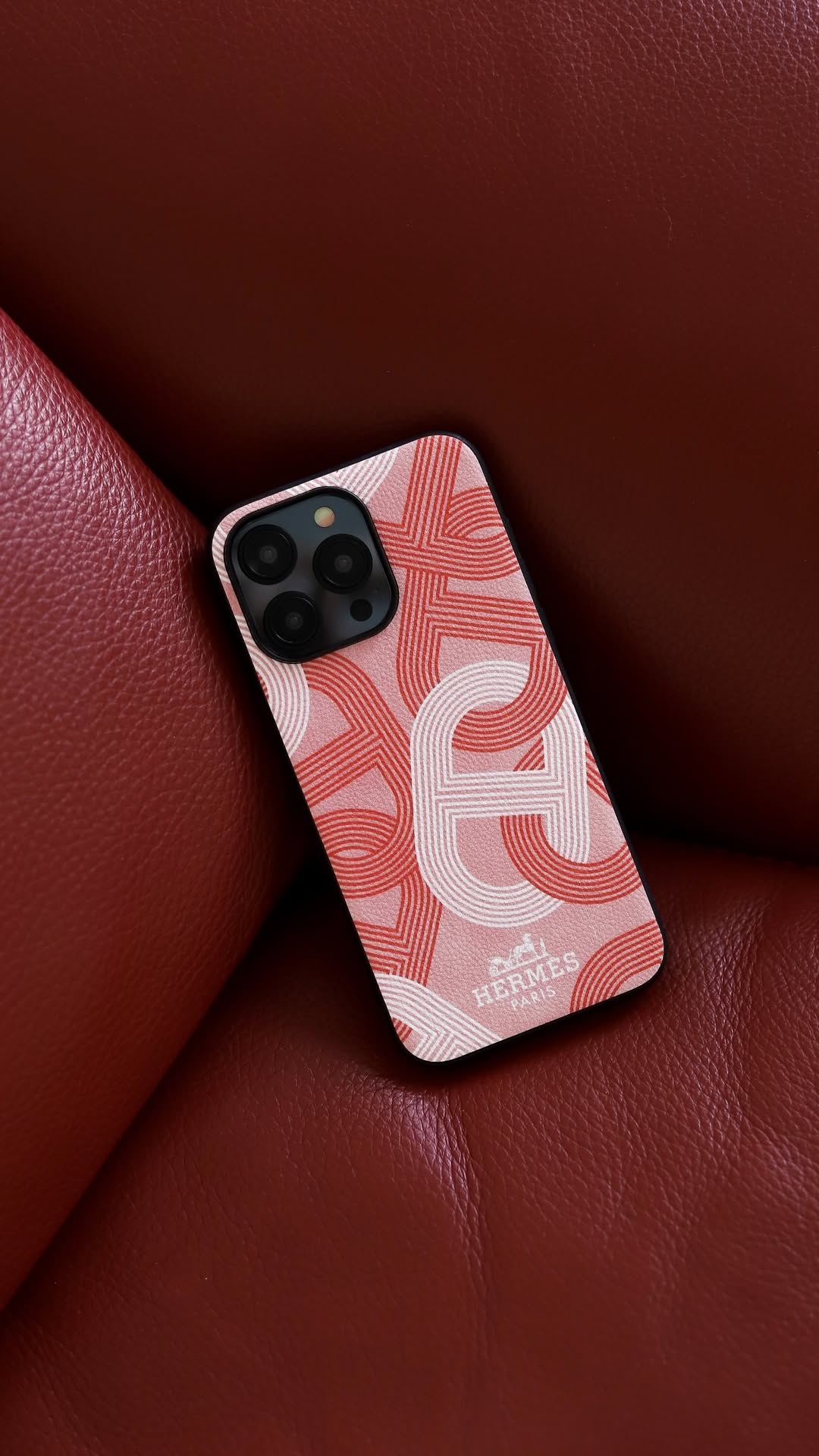 Hermes iPhone 16 Pro Max case with repeating H-pattern in pink, with a black border.