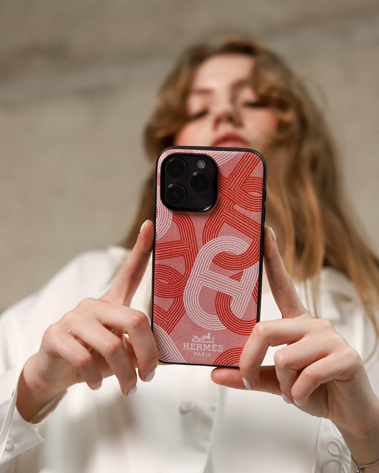 Hermes iPhone 16 Pro Max case with repeating H-pattern in pink, with a black border.